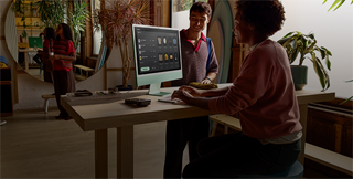 En una estancia bien iluminada, dos personas miran una serie de productos en la pantalla con vidrio nanotexturizado del iMac
